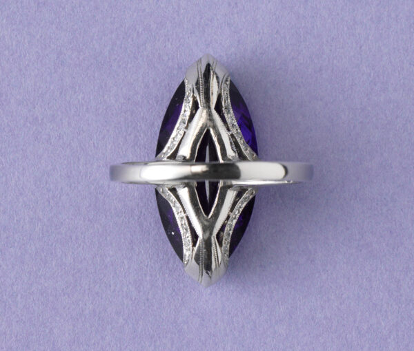 (136)	Een platina ring met een navette geslepen, prachtige amethyst aan de zijkanten van de setting vier boogjes waarin 7 kleine diamantjes op een rij gezet. Op de scheen twee baguettes in de lengte gezet. (totaal circa 0.62 karaat). ringmaat: 17 + mm. 6 ¾ US. gewicht: 6.35 gram. afmetingen amethist: 2.2 x 1 cm.  breedte scheen: 1.8 – 2 mm.