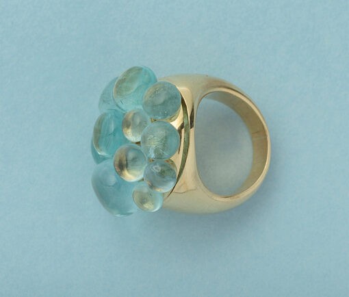 Een 18 karaat geel gouden cluster ring een cluster van 11 aquamarijn cabochons (circa 19.75 caraat) die mooi contrasteren met het goud. De ring is gesigneerd met Pomellato op een van de schouders van de ring en heeft het Italiaanse goud keur. Deze bijzondere ring maakte zijn debuut in 1996 als onderdeel van de Mora-collectie en is niet meer in productie.gewicht: 38.31 gramtafel van de ring 28.5 mm x 27.5 mmband is 6 mm.ringmaat: 18.5 mm / 8.5 US