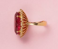 An 18 carat yellow gold ring set with a large oval facetted pink tourmaline (app. 17.40 carat with an entourage of brilliant cut diamonds (app. 0.96 carat in total, colour G-H, Vvs-Vs, gem erport AEL-Arnhem). weight: 13.6 gram ring size: 16.25 mm