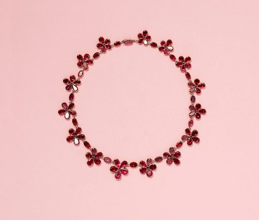 A rare and ravishing 18 carat gold Georgian necklace, composed of alternating red garnet flowers and single faceted oval garnets, all in cut away closed settings with foil backing (accentuated with small, prong-like, decorative 'nubbies'), with or without earrings English, circa 1860. weight: 36 grams length: 40.5 cm. width: 5 - 20 mm.