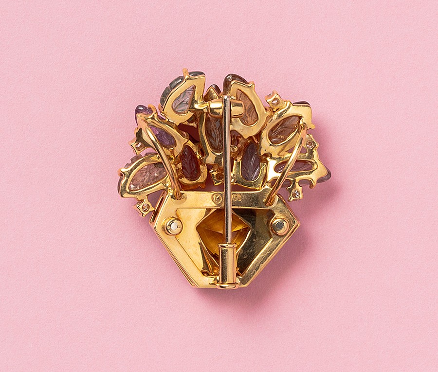 An 18 carat gold flower basket brooch, the basket itself is decorated with green guilloche enamel with a shield shaped green tourmaline, the flowers are nine leaf carved gemstones (most of them are tourmalines except the two blue ones) with six brilliant cut diamonds in between, German. weight: 15.25 grams dimensions: 3 x 3 cm