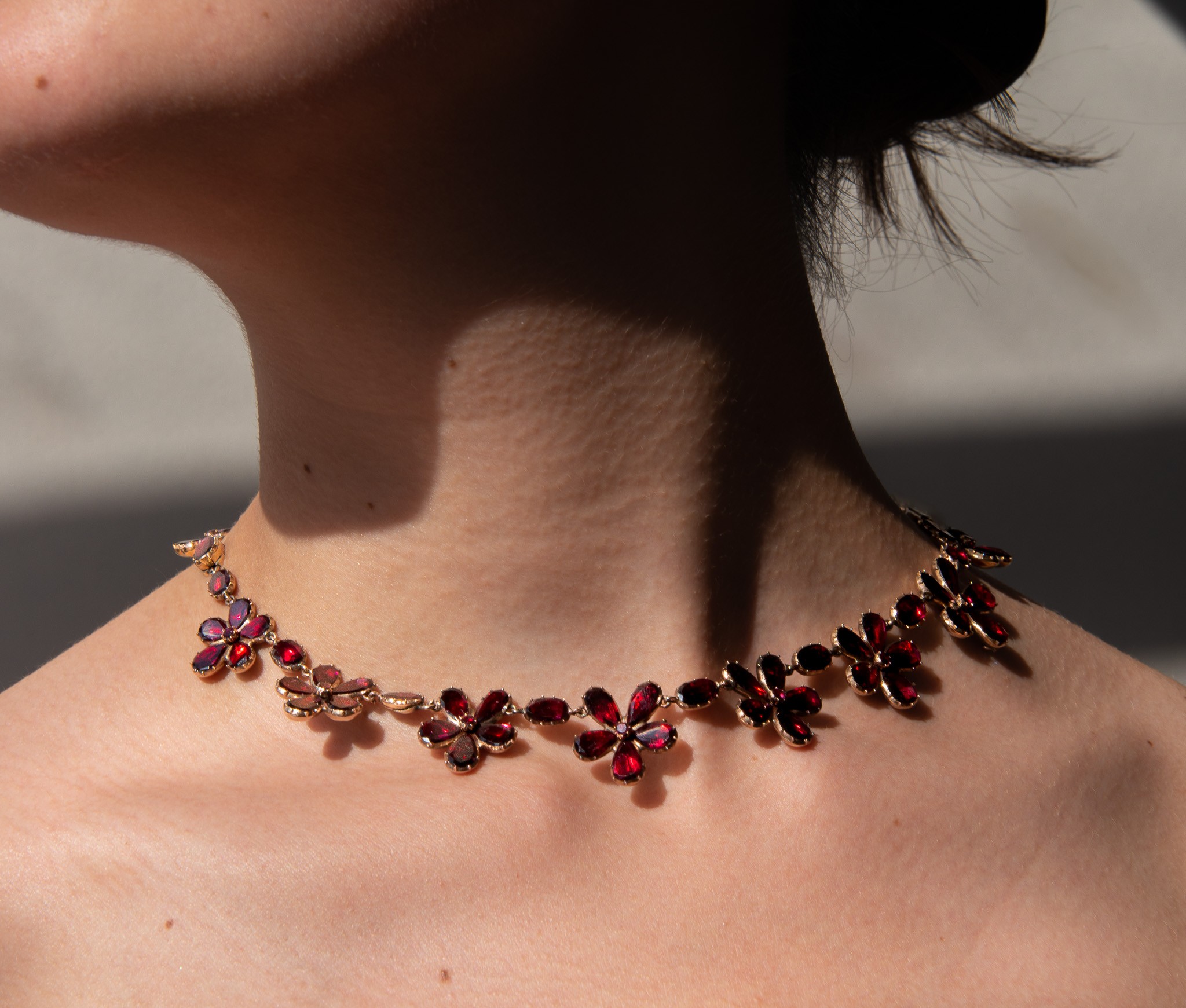 A rare and ravishing 18 carat gold Georgian necklace, composed of alternating red garnet flowers and single faceted oval garnets, all in cut away closed settings with foil backing, with or without earrings English, circa 1860. weight: 36 grams length: 40.5 cm. width: 5 - 20 mm.