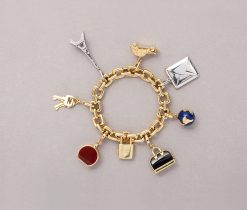 An 18 carat yellow gold oval link bracelet with seven different travelling/souvenir charms: a padlock and keys, a blue enamelled globe, the Eiffeltower in whitegold with small brilliant cut diamonds, an old Tinsnail (Citroën 2CV) with yellow diamonds in the hewadlights, a whitegold envelope (with paper) a black enamelled handbag and  a carneleon luggage charm crafted by Louis Vuitton from the 2000 Collection. This Louis Vuitton bracelet is highly collectable! Padlock keys and charms with LV monogram and French hallmarks which are stamped on most of its products, like watches, jewelry, accessories etc. Louis Vuitton is one of the world's leading international fashion houses. For six consecutive years (2006–2012), Louis Vuitton was named the world's most valuable luxury brand.weight: 164.52 gramslength: 20 - 20.5 cm / 8 - 8.2 incheswidth links: 10 mm.length largest charm: 5 cm.
