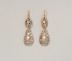 Een paar imposante 15 karaat gouden en zilveren oorbellen met een kant-achtig ontwerp, opengewerkt met krullen en bloemetjes en versierd met roos geslepen diamanten, België, circa 1820. gewicht: 16.12 gram afmetingen: 7.8 x 2.3 cm