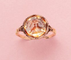 A beautiful 14-carat rose gold ring, featuring a round flat orange topaz that is foiled in a cutaway setting. The gem is engraved with an intaglio that reads 'Vivons Unis' (Let us live in unity). The ring also showcases two kissing birds under a canopy of ribbons of stars or flowers, signifying that their love was destined to be, 'written in the stars'. England or France, late 18th century. Weight: 3.55 g size: 17 mm / 6 1/2 US Width: 1.2 - 14 mm