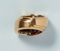 Een retro tank ring van 18 karaats goud met twaalf pavé gezette, carré geslepen saffieren (circa 1.44 karaat totaal) in een rechthoek gezet. Elke hoek wordt omhelsd door een L vorm van goud met zes oud geslepen diamanten (circa 0.84 karaat totaal) in witgoud. Frankrijk, 1980?gewicht: 10.08 gringmaat: 15 mm / 4+ USbreedte: 7 - 14 mm