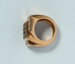 Een retro tank ring van 18 karaats goud met twaalf pavé gezette, carré geslepen saffieren (circa 1.44 karaat totaal) in een rechthoek gezet. Elke hoek wordt omhelsd door een L vorm van goud met zes oud geslepen diamanten (circa 0.84 karaat totaal) in witgoud. Frankrijk, 1980?gewicht: 10.08 gringmaat: 15 mm / 4+ USbreedte: 7 - 14 mm