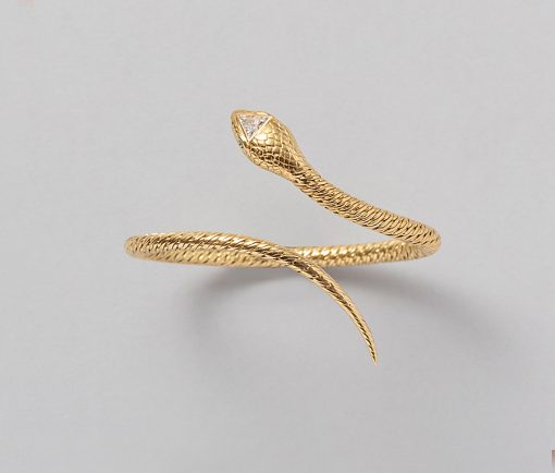 Een 18-karaats gouden flexibele gevlochten armband in de vorm van een slang met smaragden oogjes en een een triangle diamant in de kop (circa 1.30 ct, SI-EF), Frankrijk, toegeschreven Georges Lenfant. gewicht: 33.16 g maat: 56 mm goed passend voor een pols van 15-17 cm