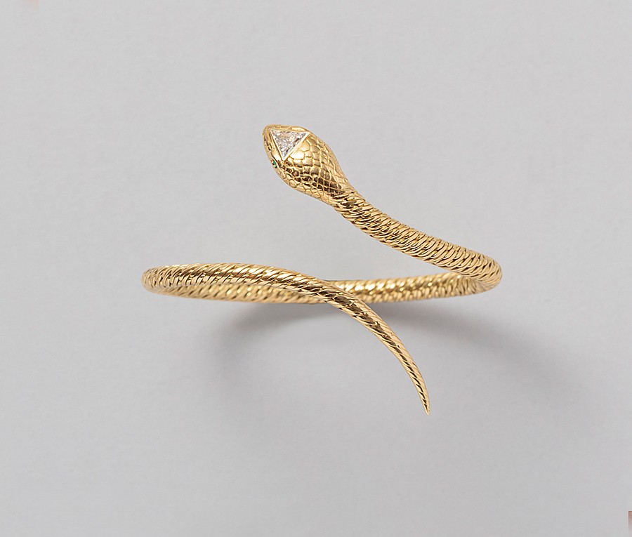 Een 18-karaats gouden flexibele gevlochten armband in de vorm van een slang met smaragden oogjes en een een triangle diamant in de kop (circa 1.30 ct, SI-EF), Frankrijk, toegeschreven Georges Lenfant. gewicht: 33.16 g maat: 56 mm goed passend voor een pols van 15-17 cm