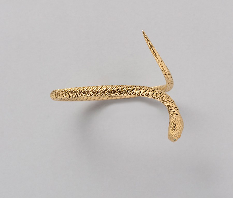 Een 18-karaats gouden flexibele gevlochten armband in de vorm van een slang met smaragden oogjes en een een triangle diamant in de kop (circa 1.30 ct, SI-EF), Frankrijk, toegeschreven Georges Lenfant. gewicht: 33.16 g maat: 56 mm goed passend voor een pols van 15-17 cm