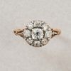 Een 18 karaat gouden en zilveren cluster ring met acht oud geslepen diamanten rondom een grotere old mine cut diamant (circa 1.10 ct totaal). Mooie decoratieve krullen op de schouders van de scheen en een geribde smalle, gouden band. Aan de onderkant van het cluster mooie stralen vanaf een cirkel in het hart. Lijkt een beetje op een stralende zon. Frankrijk, circa 1750-1775 (18e eeuw). Uil importkleur en nog een keur dat onleesbaar is. gewicht: 2.36 ringmaat: 16.5 mm/ 6 US breedte: 1.2 - 10 mm