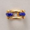 Een 18-karaats geelgouden vaste schakel ring met vier horizontale balkjes met ingelegde Lapis Lazuli. Gesigneerd en genummerd: Mauboussin Paris 23851. gewicht: 11.01 g ringmaat: 16.5 mm. / 6 US breedte: 10 mm