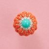Een 18-karaats geelgouden taart ring met rondom twee rijen van 12 cabochon geslepen ovale bloedkoralen. De onderste rij met iets grotere koralen en tussen de koralen een gouden randje. Boven op een bloemvorm van witgoud waarin twaalf briljant geslepen diamanten, bovenop een ronde cabochon geslepen turkoois gezet in zes geelgouden klauwtjes. Onderaan de ring een golvende rand van gedraaid gouddraad en twee gouden bolletjes op de scheen die bestaat uit vijf banden aflopend van breed naar smal, numbered 2553, circa 1960. gewicht: 27 g ringmaat: 16+ mm / 5 1/2 US afmetingen: 27.2 (breedte ring ) x 24 (hoogte) mm breedte scheen: 4.2 - 12 mm