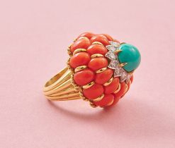 An 18k yellow gold cake ring with two rows of 12 oval cabochon-cut corals around it. The bottom row has slightly larger corals and a gold border between the corals. On top is a white gold flower set with twelve brilliant-cut diamonds, topped with a round cabochon cut turquoise set in six yellow gold claws. At the bottom of the ring is a border of twisted gold wire and two gold balls on the shank, which consists of five bands tapering from wide to narrow, numbered: 2553, circa 1960. weight: 27 g ring size: 16+ mm / 5 1/2 US dimensions: 27.2 (ring width) x 24 (height) mm shank width: 4.2 - 12 mm