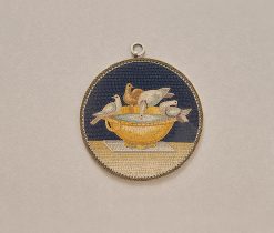 Een micromozaïek gemaakt van minuscule glas draden (tesserae) in verschillende vormen en kleuren, waarmee de voorstelling als het ware is geschilderd. Het mozaïek stelt de duifjes van Plinius, toegeschreven aan het atelier van Giacomo Raffaelli, vervaardigd rond 1800 in Rome in een latere zilveren montage. De Vaticaanse mozaïek studio’s waren al in 1576 om de schilderijen in de Sint Pieter te vervangen door mozaïek, maar in de 18e eeuw ontstond er een ware rage en werd het Romeinse mozaïek zowel als kunstwerk als souvenir zeer populair. Aanleiding hiervoor was de vondst van een vloer fragment van mozaïek; de duifjes van Plinius, het meest geliefde en bekendste mozaïek uit de oudheid. Kardinaal Giuseppe Furietti (1685 – 1764) vond het fragment tijdens het opgraven van de Villa Adriana in Tivoli in 1737. Volgens Furietti was dit fragment het originele Griekse fragment door Sosos van Pergamon waar Plinius de oudere over heeft geschreven. Plinius roemt dit mozaïek als de perfecte kunst. Hij schrijft: “Er is een prachtige duif aan het drinken en de schaduw van zijn hoofdje wordt gereflecteerd in het water, de andere duiven wassen zich en zonnen op de rand van de schaal”. Hoewel Furietti’s fragment nu wellicht als een kopie voor Keizer Hadrianus wordt gezien, werd het in 1764 door Paus Clemens XIII gekocht en naar het Capitolijns museum gebracht, waar duizenden bezoekers het nu dagelijks bewonderen. Dit vroeg 19e eeuwse micromozaïek is een zeer fijne en gedetailleerde kopie van de duifjes uit het Capitool. gewicht: 45 g diameter: 7.5 cm literatuur : voir Domenico PETOCHI, I m osaici minuti Romani del secoli XVIII-XIXe siècle, page 108, n°29.