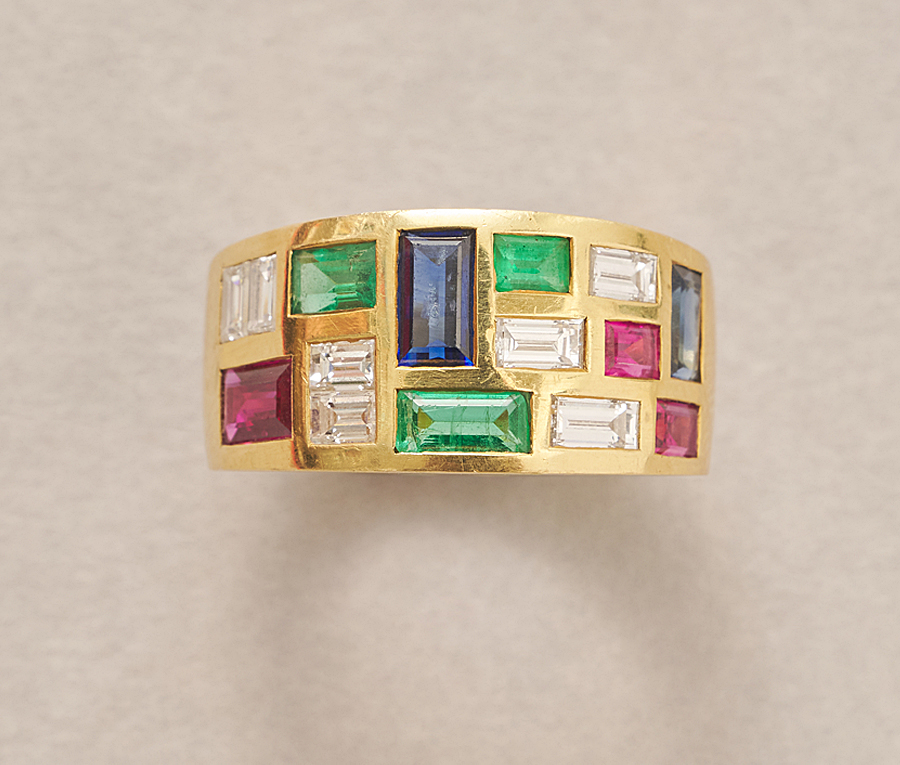 Een 18-karaats gouden brede band ring met 7 baguette geslepen diamanten (circa. 0.86 ct IF- G), 2 Thaise saffieren (circa 0.89 ct),3 Thaise robijnen (circa 0.75 ct) en 3 Brazilaanse smaragden (circa 0.55 ct) allen flush gezet, gesigneerd and genummerd: Wempe, 2541, Duitsland, circa 1980, met certificaat.gewicht: 9.48 gringmaat: 17 mm / 6.50 US / 53-54afmetingen: 11 x 3 mm