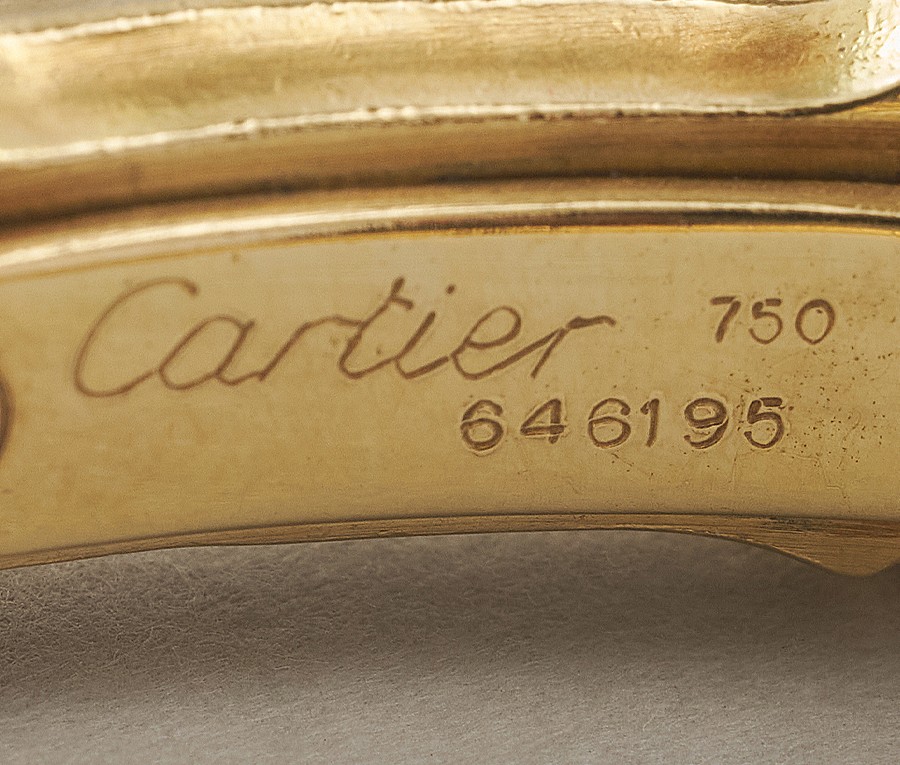 Een 18-karaats geelgouden flexibele klem armband “Bamboo” in de vorm van een om de arm gebogen bamboe steel van negen segmenten, de drie middelste segmenten pavé bezet met briljant geslepen diamanten in verschillende maten (209 stuks, totaal diamantegewicht geschat in zettingen 4 ct.), in de band is een veer voor de spanning gemonteerd, onderzijde van de band is open. Gesigneerd Cartier, Parijs, maat 2 en 646195, meesterteken P gekruisde korenaren> voor Pierre Brun. Gewicht 57.8 g binnen diameter: 56 x 47 mm maat: 2, 15 - 17.5 cm breedte: 7 - 8.83 mm.