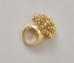 Een brede 18-karaats geelgouden ring met steeds vier bewegende balletjes op een gouden staafje, in een kogelconstructie, aan sliertjes, gesigneerd, genummerd en gedateerd: Cartier, 50731, 1999, model "Perruque" met Frans meesterteken. gewicht: 36.43 g ringmaat: 16.75 mm / 6 1/4 US breedte: 7 - 31 mm