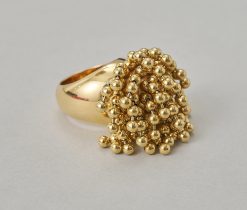 Een brede 18-karaats geelgouden ring met steeds vier bewegende balletjes op een gouden staafje, in een kogelconstructie,  aan sliertjes, gesigneerd, genummerd en gedateerd: Cartier, 50731, 1999, model "Perruque" met Frans meesterteken.gewicht: 36.43 gringmaat: 16.75 mm / 6 1/4 USbreedte: 7 - 31 mm