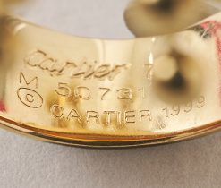 Een brede 18-karaats geelgouden ring met steeds vier bewegende balletjes op een gouden staafje, in een kogelconstructie, aan sliertjes, gesigneerd, genummerd en gedateerd: Cartier, 50731, 1999, model "Perruque" met Frans meesterteken. gewicht: 36.43 g ringmaat: 16.75 mm / 6 1/4 US breedte: 7 - 31 mm