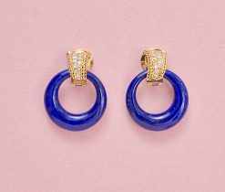 Een paar 18-karaats geelgouden oorbellen in een gebogen halfronde band op het oor, twee dun gedraaide bandjes goud aan weerszijden van 13 briljant geslepen diamanten aflopend in maat. Eraan te hangen 4 paar hoops van speciale van smal naar breder wordende gladde ringen van groene granaat, lapis lazuli, onyx en ivoor. gewicht: 41.77 g (samen, excl witte ivoren hoops). afmetingen: 3.8 x 2.8 mm
